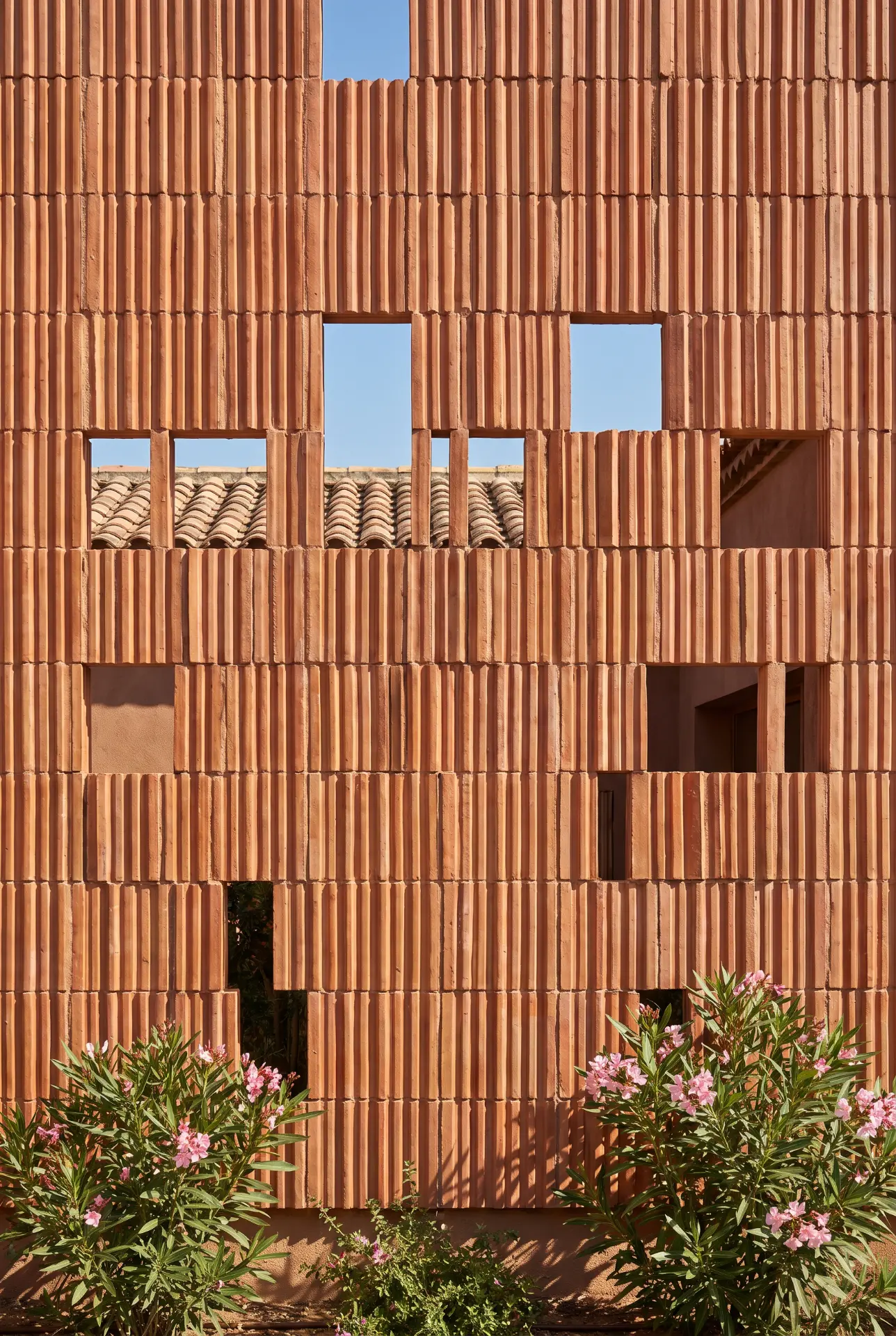 Stacked terracotta tile facade with open apertures