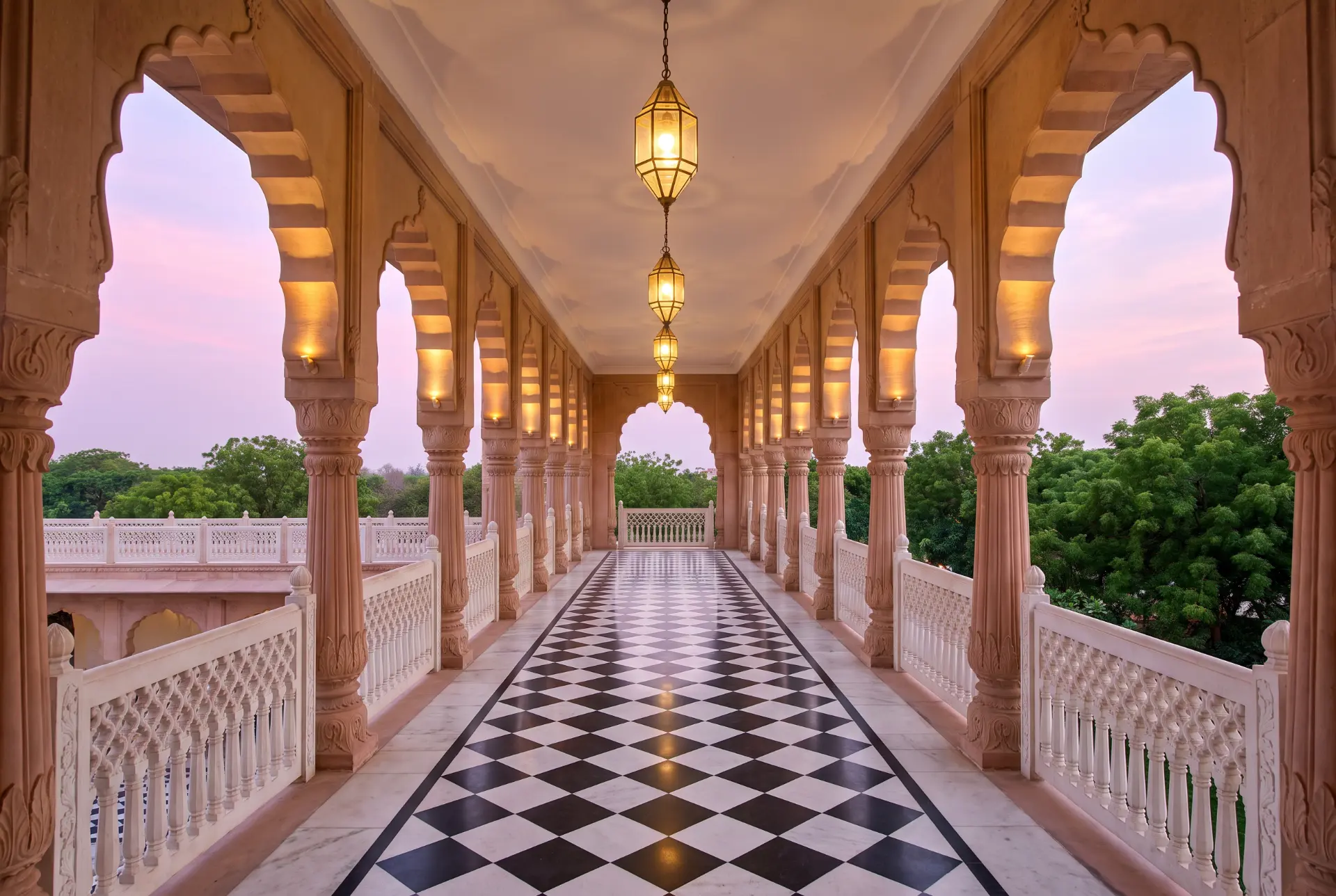 Sandstone arcade with lanterns at dusk